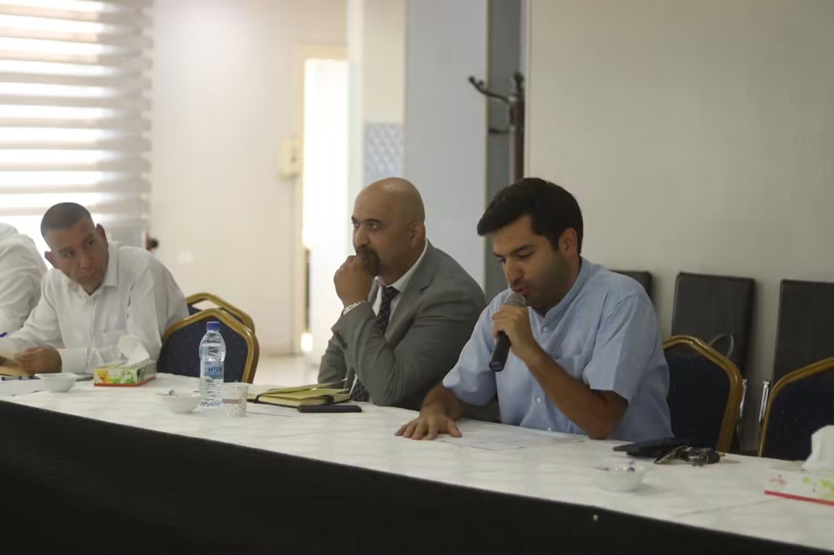 Three panellists at a discussion table, one speaking into a microphone