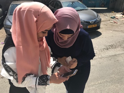 Two young women looking at a mobile phone on the street